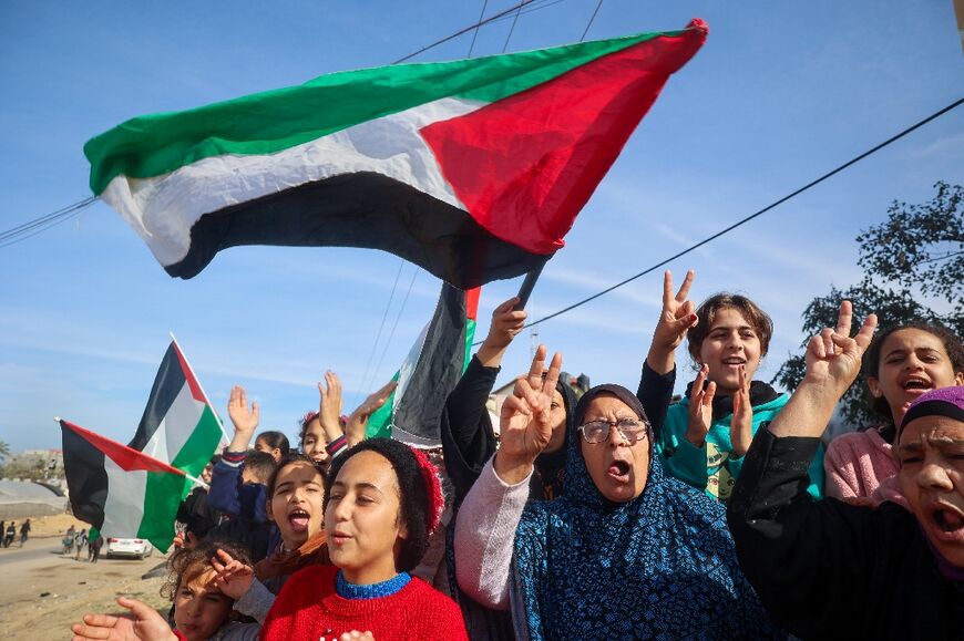 Displaced Gazans wave Palestinian flags as they return to Rafah, southern Gaza, at the start of the ceasefire