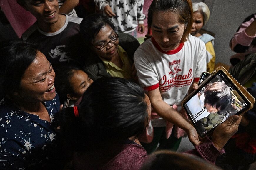 Wiwwaeo Sriaoun (L), the mother of Thai farm worker Watchara Sriaoun who was held hostage in Gaza, reacts as she receives an image of her son (R) being released