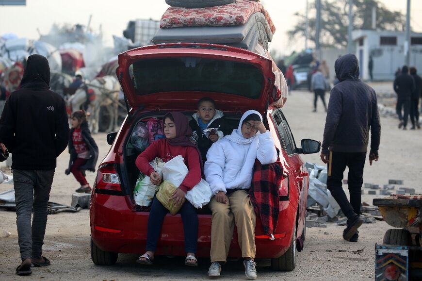 Displaced Palestinians wait along the Salah al-Din road in Nuseirat near the blocked Netzarim corridor, unable to cross into northern Gaza