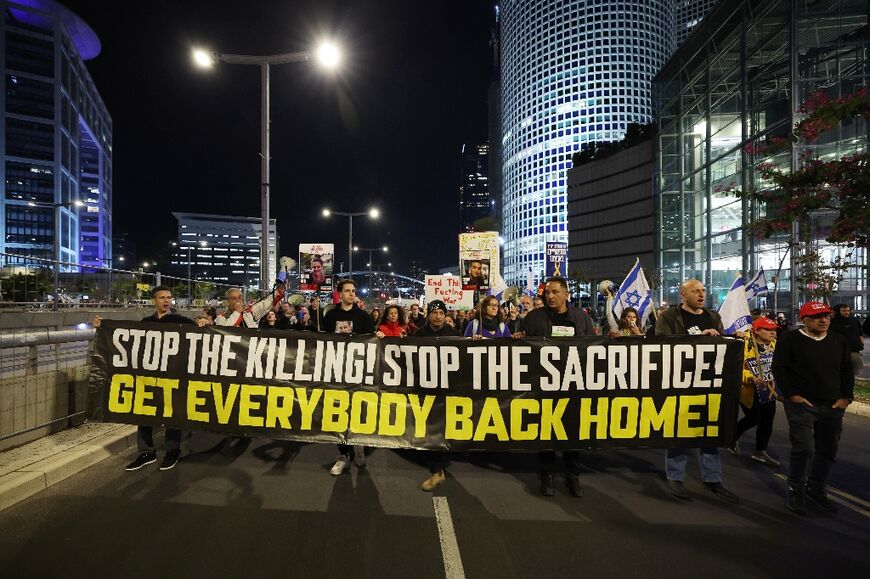 Demonstrators in Tel Aviv raise placards and wave flags during a protest calling for the release of hostages held captive in Gaza