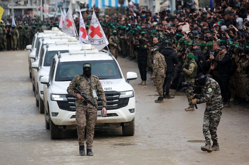 A Palestinian Hamas fighter precedes Red Cross vehicles arriving in Nuseirat, central Gaza, to receive three Israeli hostages freed by militants under a ceasefire deal