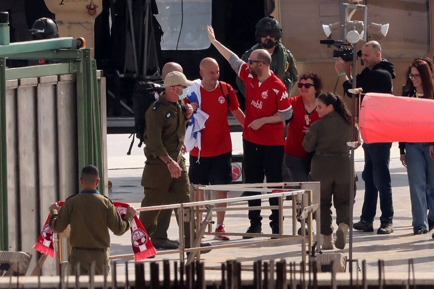 Newly-released Israeli-Argentine hostage Yair Horn (C-in red), flanked by relatives and security forces, waves after disembarking from a military helicopter at a medical centre in Tel Aviv following his release from captivity in Gaza