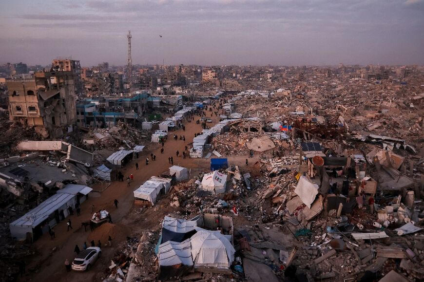 Palestinians walk past tents lining the streets in a largely destroyed part of Jabalia, in the northern Gaza Strip