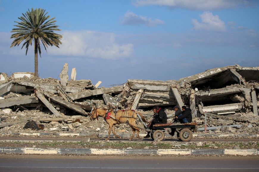 People ride past the rubble of a destroyed building in the central Gaza Strip on Thursday