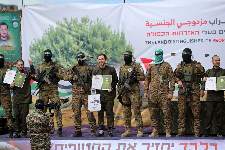 Hamas militants parade newly-released Israeli hostages (L to R) Elia Cohen, Omer Shem Tov and Omer Wenkert on stage in Nuseirat in the central Gaza Strip