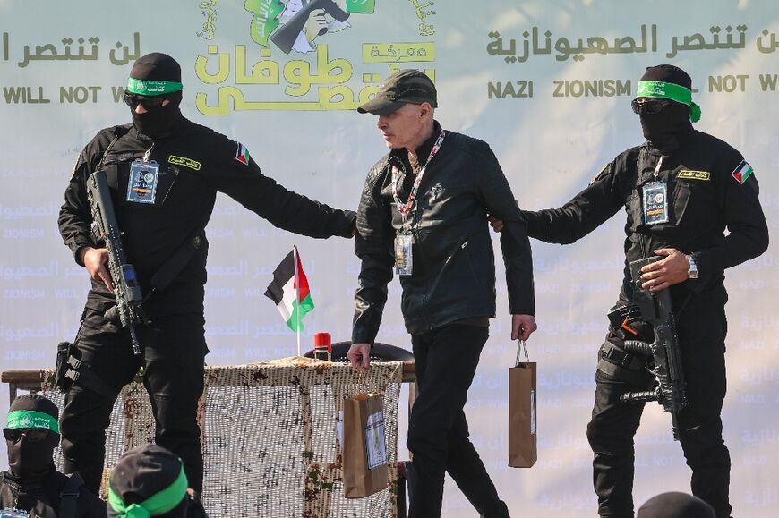 Palestinian militant group Hamas fighters escort American-Israeli hostage Keith Siegel on a stage before handing him over to a Red Cross team in Gaza City