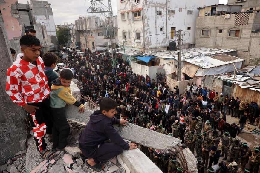 Children look on as Hamas fighters and mourners perform the noon prayer during the funeral for top Hamas commander Marwan Issa in central Gaza's Bureij refugee camp