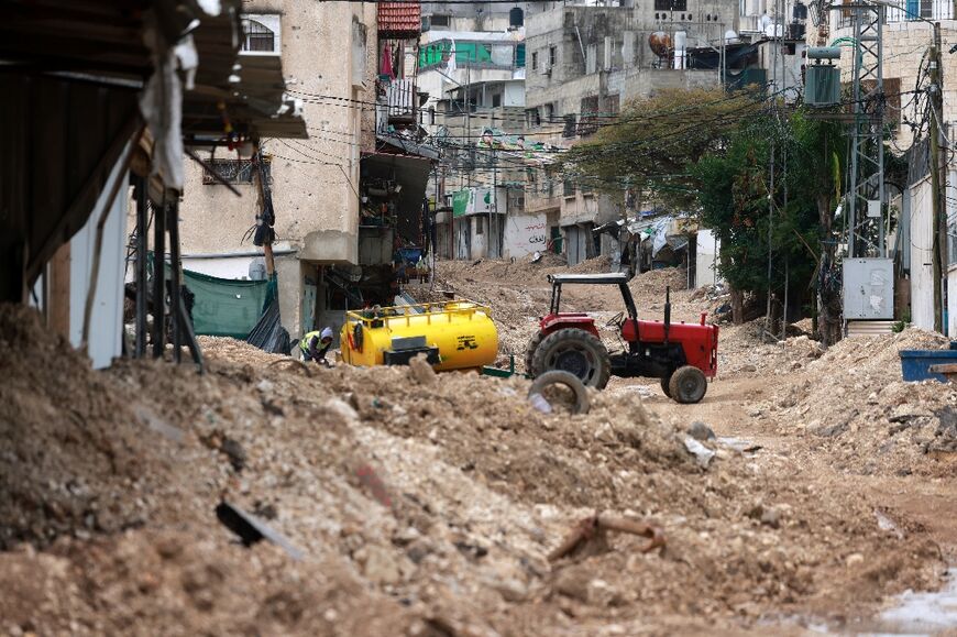 A man supplies water to residents of a building along a street destroyed by Israeli bulldozers, at the entrance to the occupied West Bank refugee camp of Tulkarem