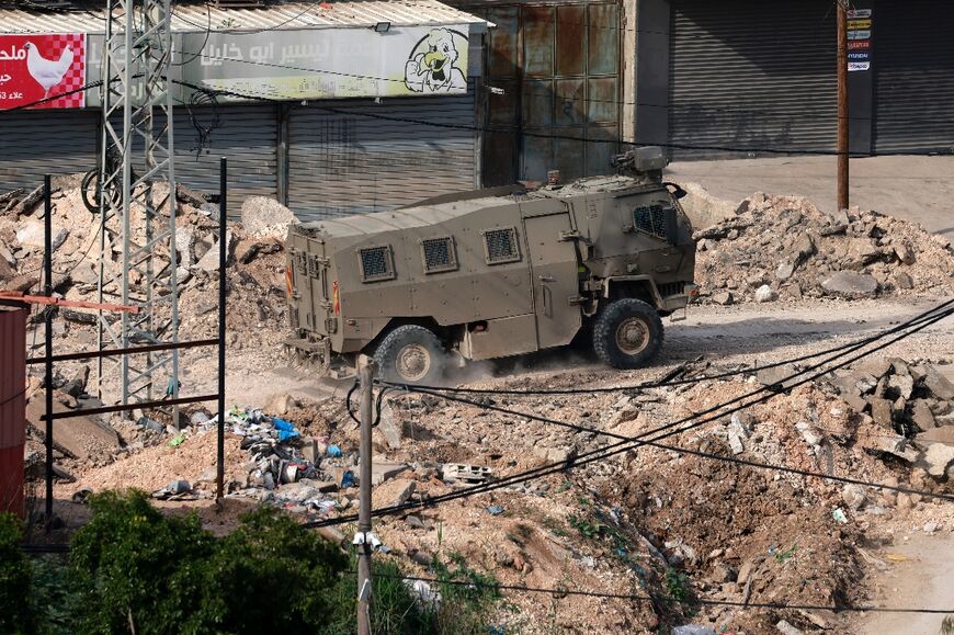 An Israeli military vehicles drives along a damaged street during a military raid in the Faraa camp for Palestinian refugees, south of Jenin in the occupied West Bank