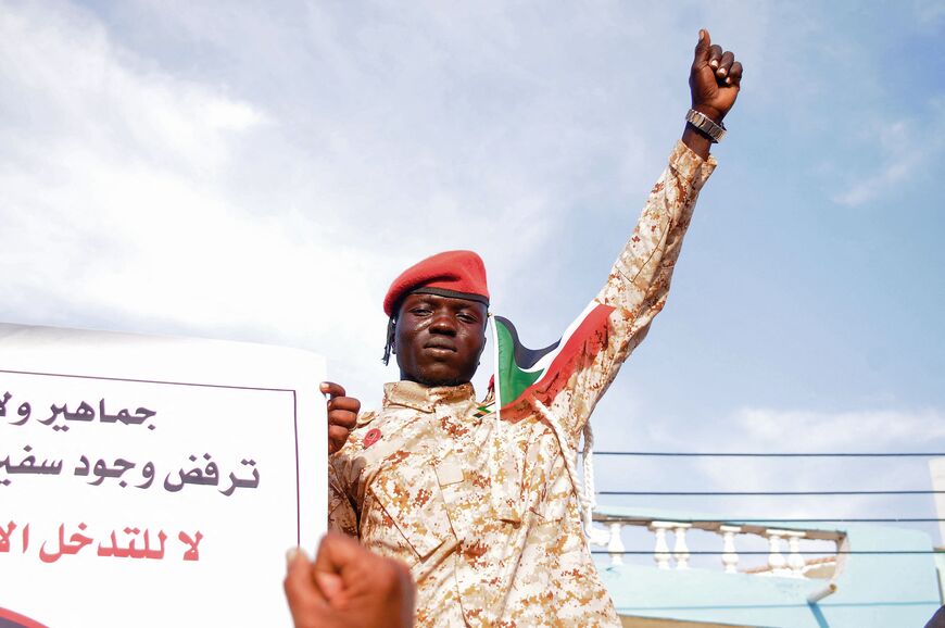 A supporter of Sudan's army joins protesters against the United Arab Emirates' influence in internal Sudanese politics in Port Sudan on April 20, 2023. The complete Arabic slogan on the banner reads: "The people of (Sudan's) Red Sea state reject the presence of the UAE ambassador in eastern Sudan. No to the foreign interference in the country's affairs." - The loyalists to the army chief were protesting against the presence of the ambassador of the United Arab Emirates, which has been accused of links to th