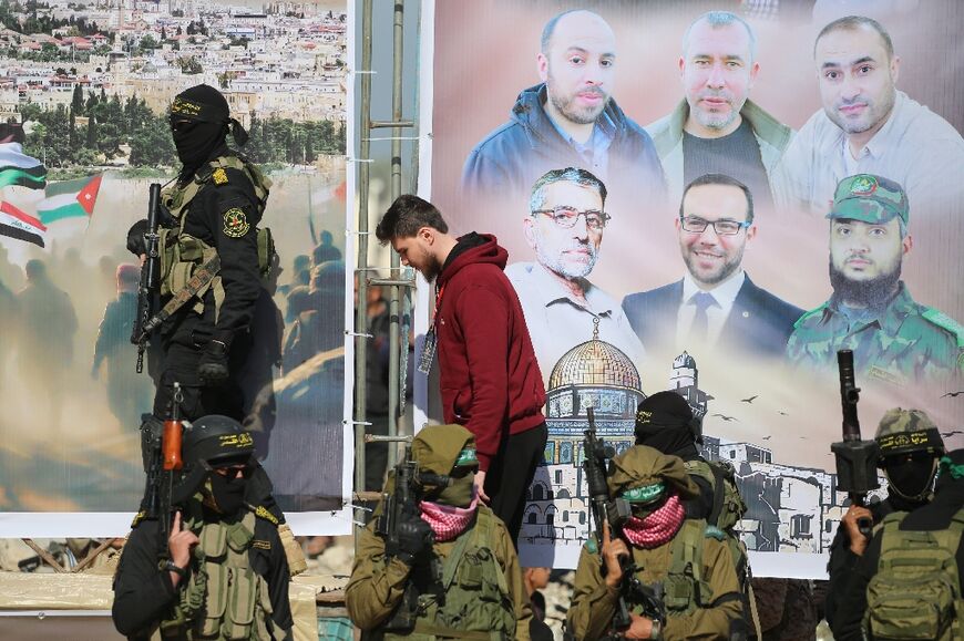 Israeli-Russian hostage Sasha Trupanov (C), surrounded by armed Palestinian militants, walks on to a stage where he and two other captives were forced to speak in front of a crowd during a choreographed release ceremony