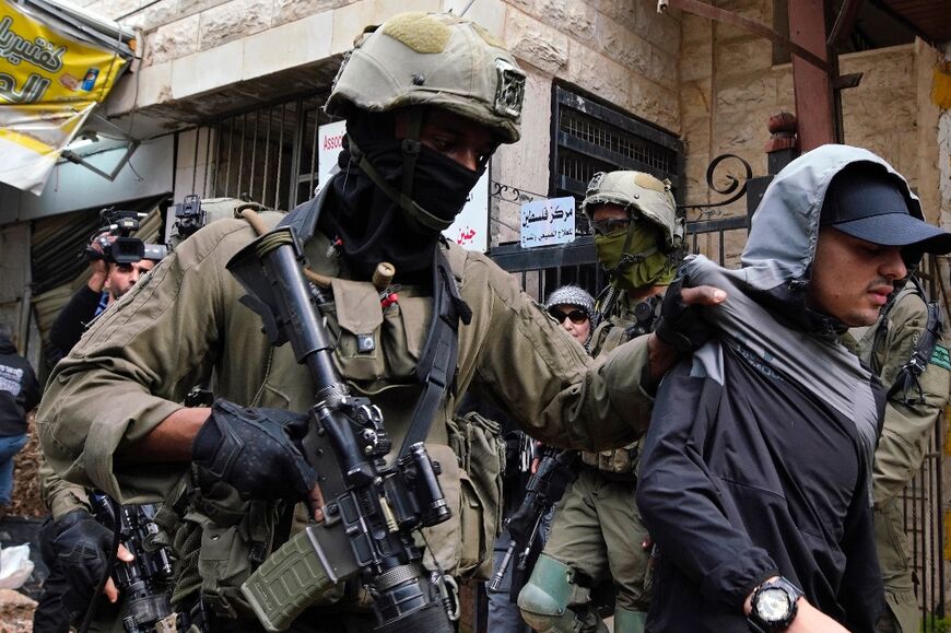 Israeli soldiers on February 19, 2025, detain a youth after preventing access to Palestinians waiting to be let back in to the Jenin refugee camp in the occupied West Bank