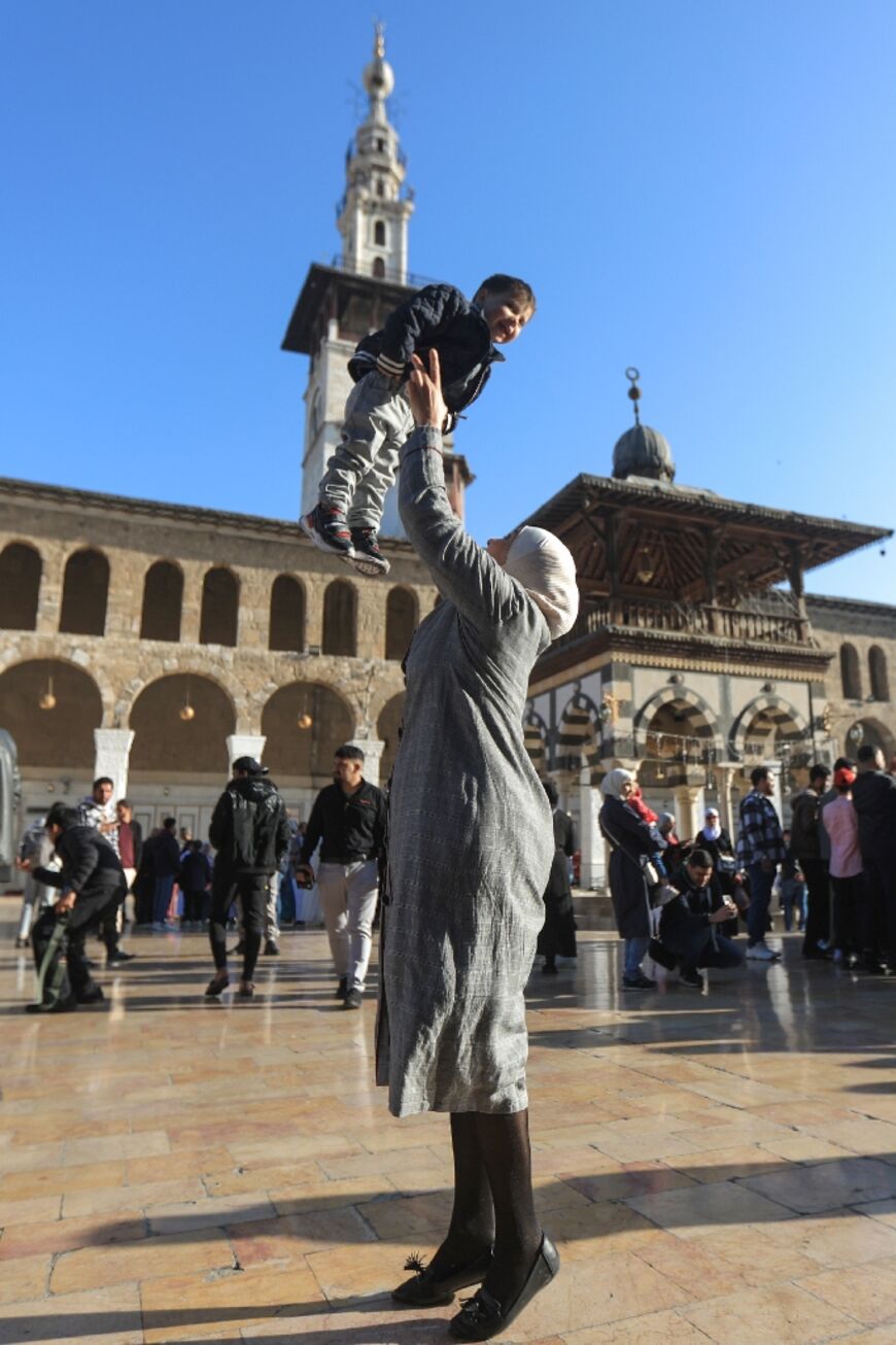 A woman celebrates with a child on the first day of the Eid al-Fitr holiday, the first such celebration since the overthrow of Bashar al-Assad