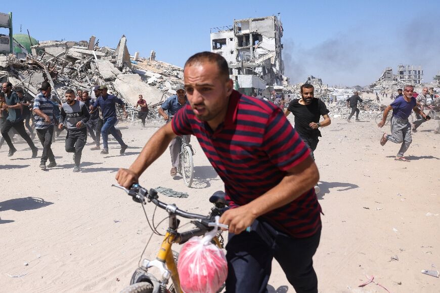Palestinians run for cover during an Israeli drone strike in Jabalia, in the northern Gaza Strip