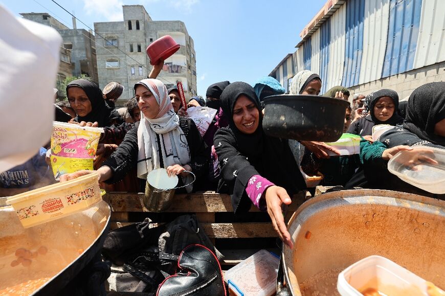 Palestinians queue for food distributed by a charity kitchen at the Nuseirat refugee camp in central Gaza