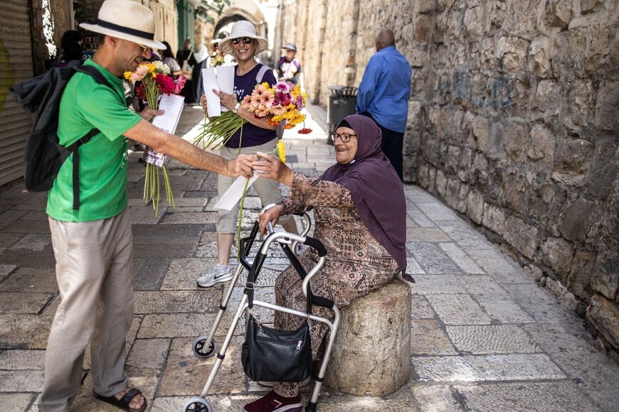 Peace activists hand out flowers to Palestinians in the Old City on Jerusalem Day