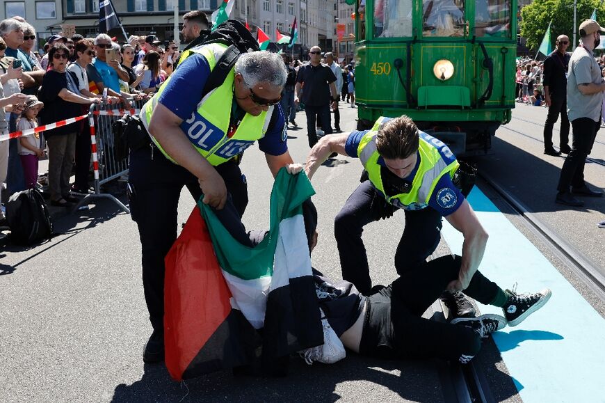 Police officers remove a protestor holding a Palestinian flag 