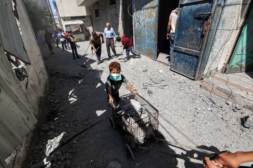 A man and boy transport a cart loaded with rubble following Israeli bombardment in the Bureij camp for Palestinian refugees in central Gaza