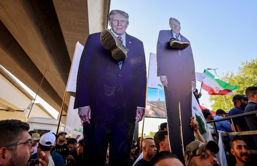 Supporters of Iraqi pro-Iran groups hold cutouts of US President Donald Trump with a shoe around the neck during a protest in support of Iran in Baghdad 