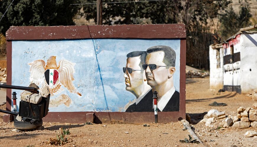 A mural depicting the coat of arms of the Syrian Arab Republic and portraits of ousted President Bashar al-Assad (L) and his brother Maher al-Assad.
