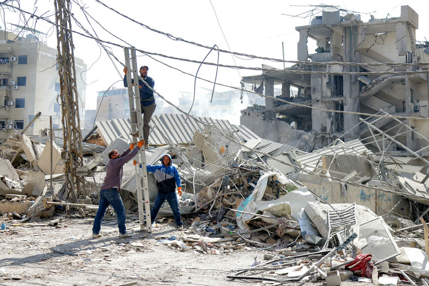 Men stand to fix a ladder for a man attempting to repair a cable by the rubble of a collapsed building at the site of an overnight Israeli airstrike in the Hadath neighbourhood of Beirut's southern suburbs on June 6, 2025. Israel warned on June 6 that it will keep striking Lebanon until it disarms militant group Hezbollah, hours after it hit south Beirut in what Lebanese leaders called a major ceasefire violation. The attack on what the Israeli military said was Hezbollah's underground drone factories came 