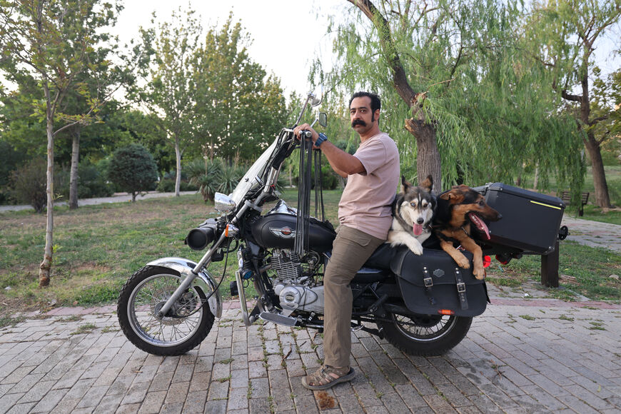 An Iranian arrives with his dogs on the back of his motorcycle in a park in Tehran on June 8, 2025. Iranian authorities have expanded a ban on walking dogs in public to multiple cities nationwide, citing public health, social order and safety concerns, domestic media reported on June 8. Owning and walking dogs has been a contentious topic since the 1979 Islamic revolution in Iran, though there is no law outrightly banning dog ownership. (Photo by ATTA KENARE / AFP) (Photo by ATTA KENARE/AFP via Getty Images