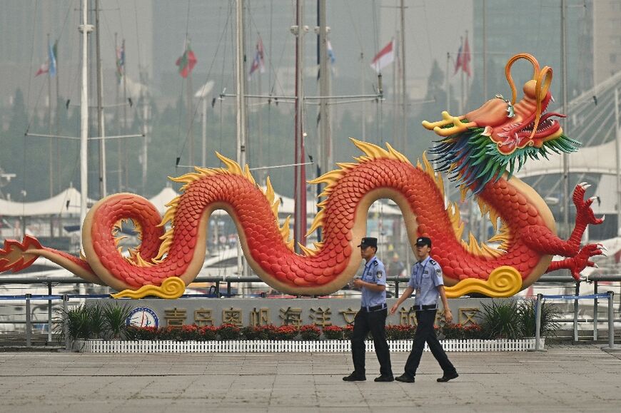 Police officers walk past a dragon sculpture as they patrol the venue hosting the Defence Ministers' Meeting of the Shanghai Cooperation Organization (SCO) Member States in Qingdao, in eastern China's Shandong province on June 26, 2025.