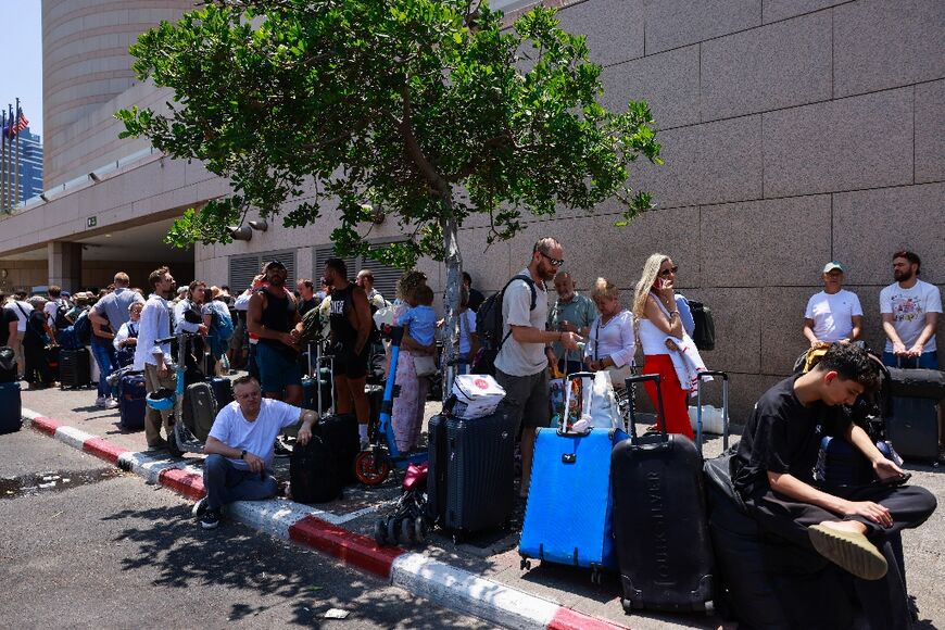People arrive with their luggage before the departure of buses slated to evacuate foreign passport holders, mainly European and Polish, out of Israel, at a meeting point in Tel Aviv