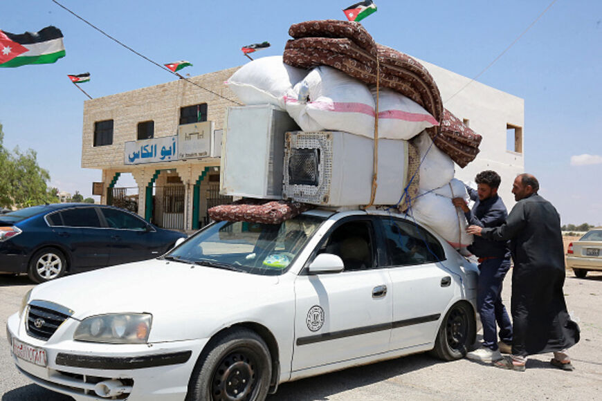 Syrian refugee men load a car with belongings as they prepare to move from the Jordan-Emirati camp in Azraq, east of Amman, on their way back to Daraa in southern Syria, on June 3, 2025 ahead of the Muslim Eid al-Adha holiday. (Photo by Khalil MAZRAAWI / AFP) (Photo by KHALIL MAZRAAWI/afp/AFP via Getty Images)