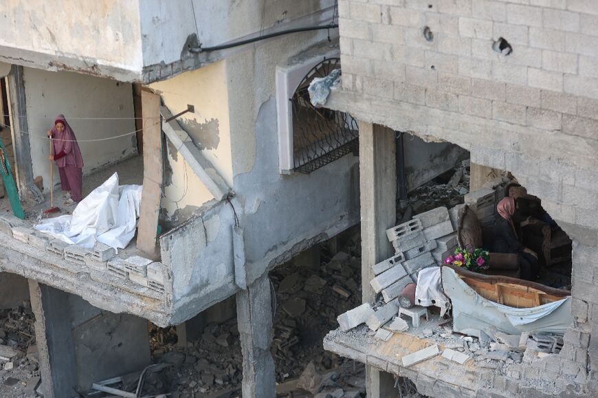 A Palestinian woman clears debris from her home as he neighbour inspects the damage after an Israeli strike on the Al-Shati refugee camp, west of Gaza City, on July 9, 2025