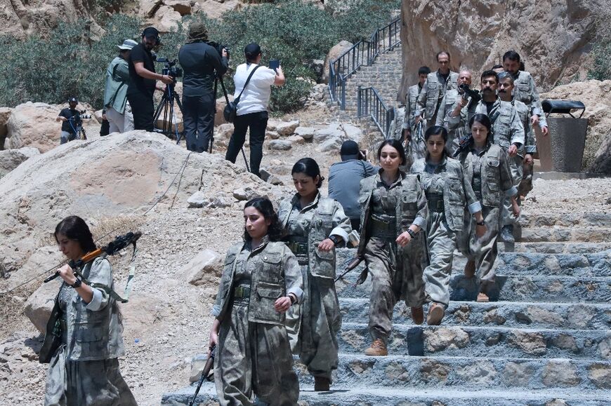 Half of the fighters were men and half women, their faces uncovered as they came forward to deposit their weapons in a giant conical fire pit set up on the stage 