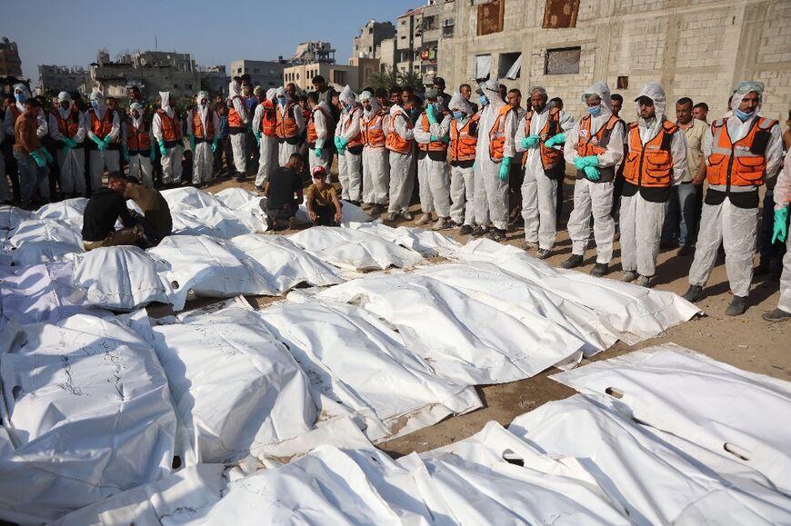 Civil Defense members stand by after laying out body bags containing the remains of members of the Shahebar family, who were buried in temporary graves, as they are brought to a cemetery in Gaza City  Civil Defense members stand by after laying out body bags containing the remains of members of the Shahebar family, who were buried in temporary graves, as they are brought to a cemetery in Gaza City