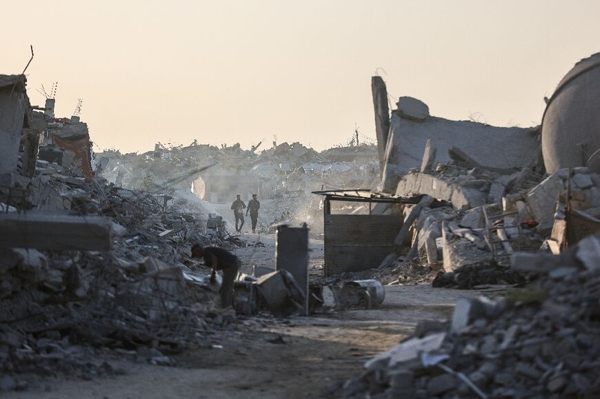 Palestinians walk amid the rubble of destroyed buildings in the Sheikh Radwan neighbourhood of Gaza City
