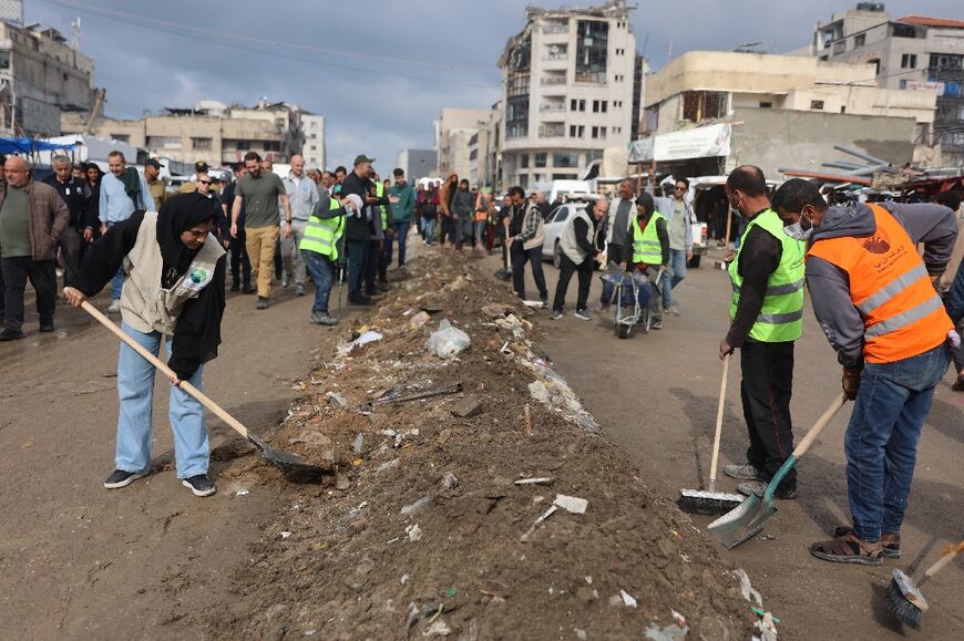 People use brooms to sweep a road in the Gaza Strip