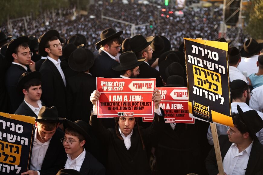 An ultra-Orthodox Jewish man holds up a placard during a protest against conscription