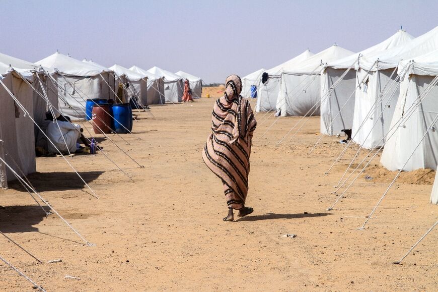 A Sudanese woman who fled El-Fasher walks past tents at Al-Dabbah refugee camp