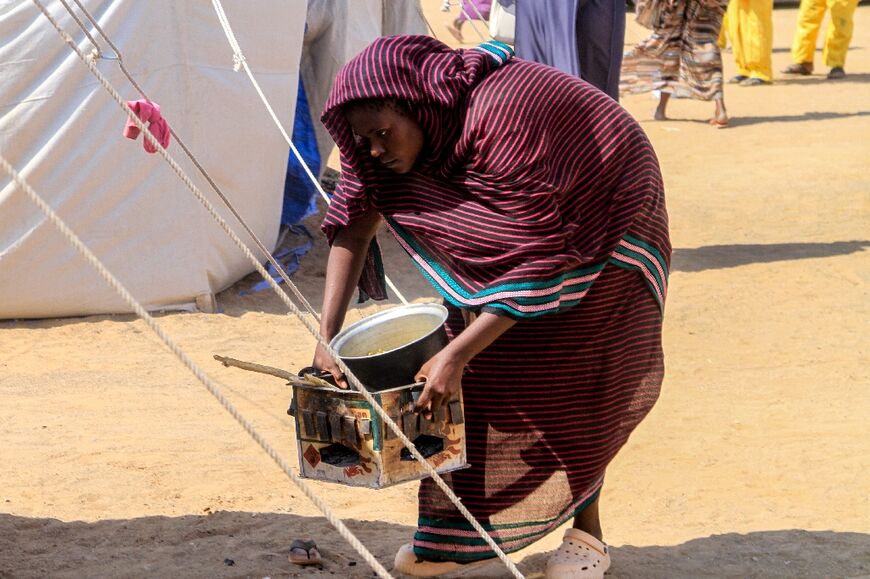 A woman who fled El-Fasher prepares a meal at the refugee camp in the northern town of Al-Dabbah