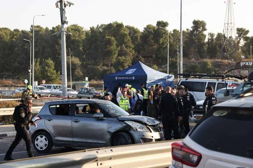 Israeli security forces stand next to a damaged car at the Gush Etzion Junction