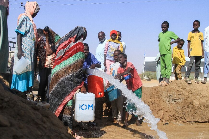 Sudanese who fled El-Fasher fill jerrycans with water at the Al-Dabbah camp