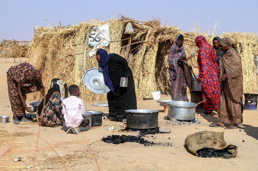 Sudanese people who fled El-Fasher prepare a meal at Al-Dabbah refugee camp
