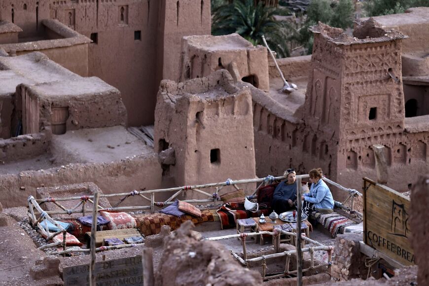 Tourists drink tea on a terrace cafe at the historic ksar (fortified village) of Ait Benhaddou, known for its earthen clay architecture and listed as a UNESCO World Heritage site since 1987, in Morocco's southern province of Ouarzazat on November 22, 2024. (Photo by AFP) (Photo by -/AFP via Getty Images)