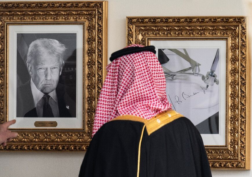 Crown Prince and Prime Minister of the Kingdom of Saudi Arabia Mohammed bin Salman looks at a framed photo of US President Donald Trump (L) next to a picture of an "autopen" to represent former President Joe Biden