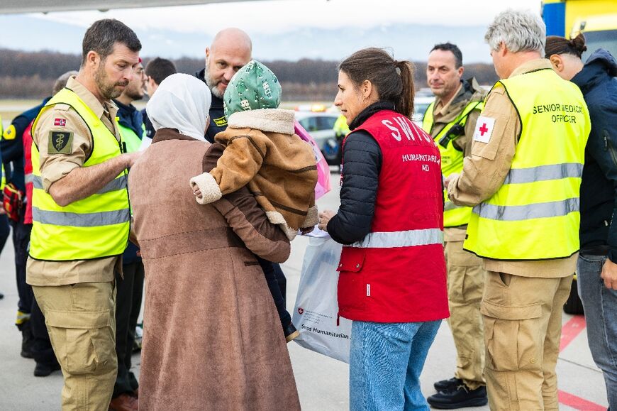A woman and her baby arrive in Geneva among  13 children and 51 family members moved from Gaza under medical evacuations