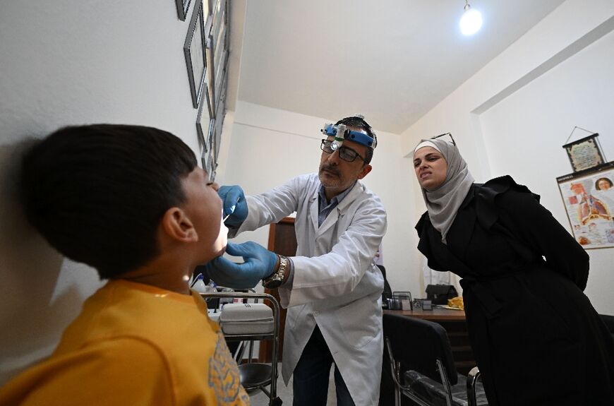 Hussam Jamus, a doctor who has returned to Daraya, treats a young patient in his surgery