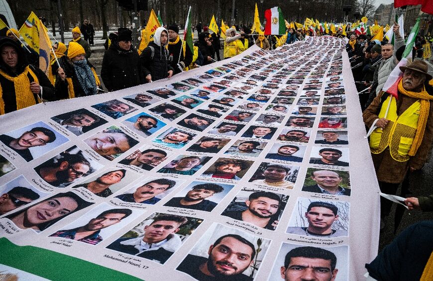 At the MEK demo, protesters display a banner featuring portraits of alleged victims of the Iranian government 