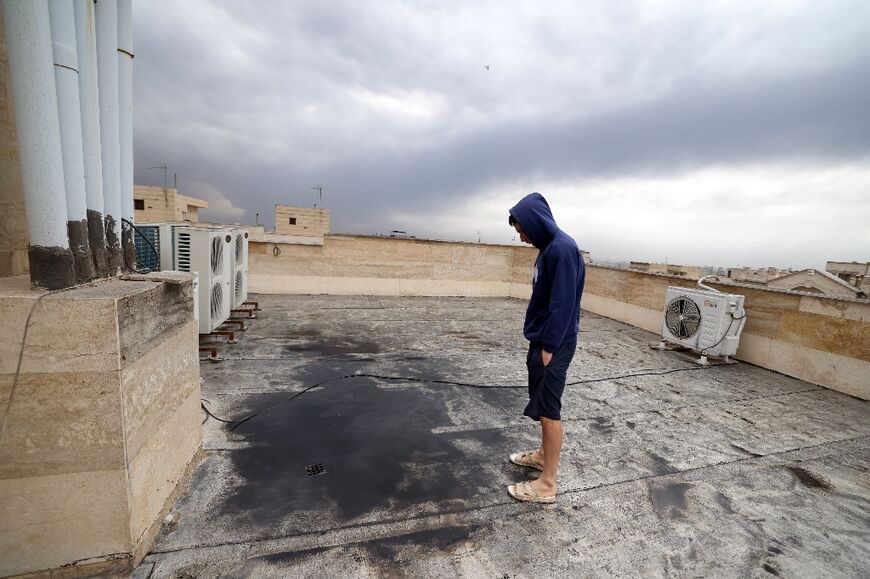 A Tehran resident inspects soot on the roof of his home after the oil sites were hit