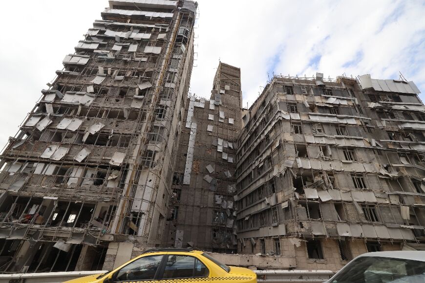 Cars drive past the damaged facade of the Gandi Hospital in Iran