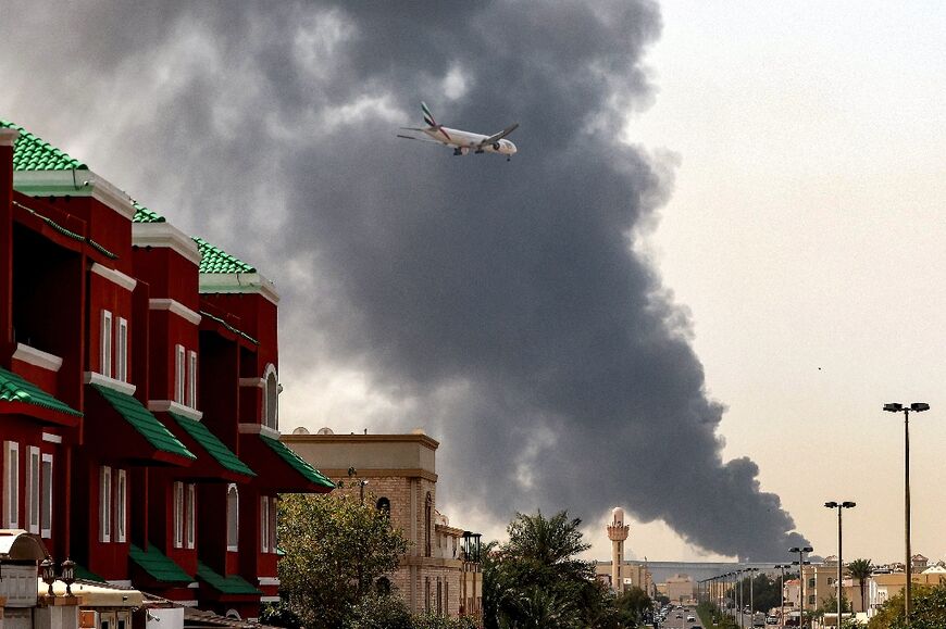 A plane comes into land as smoke rises near Dubai International Airport 