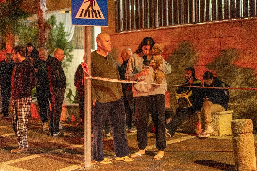 People gather outside a building hit by a projectile in a city in outskirts of Tel-Aviv