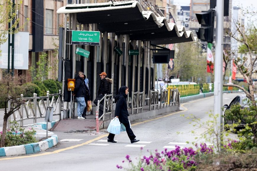 An Iranian woman walks past a bus stop in Tehran on March 31, 2026